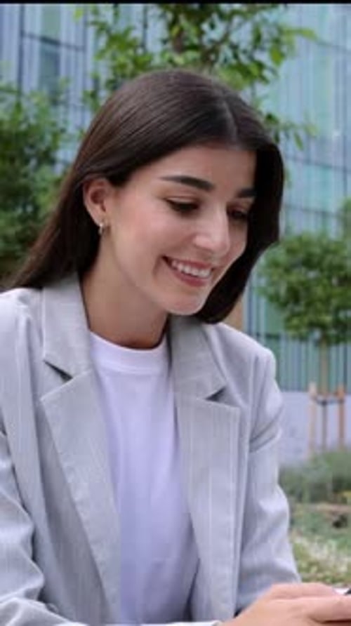 Happy Businesswoman in Smart Casual Using Mobile Phone Over Office Buildings