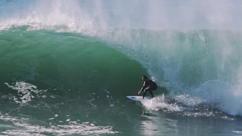 Surfer locks into emerald barrel before wave crashes in cascade of foam
