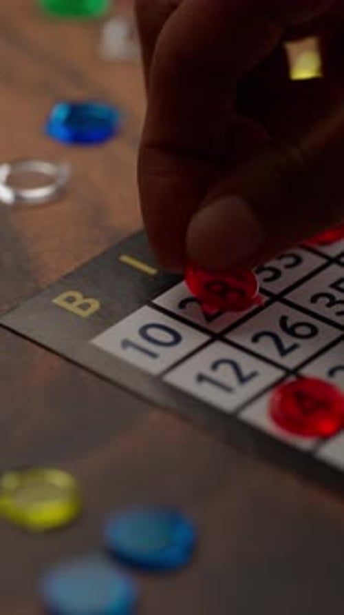 Vertical Video, The Fingers Of A Latin Woman Place Red Chips On A Bingo Board