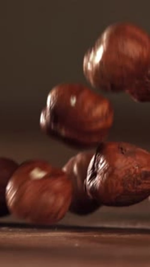 Haselnüsse fallen auf einen Holztisch, gefilmt mit einer Hochgeschwindigkeitskamera mit 1000 Bildern pro Sekunde