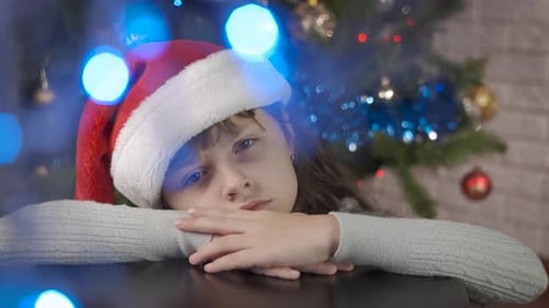 Child Wearing Santa Hat Resting at Table