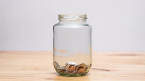 Coins Fill Jar on Wood Table Top
