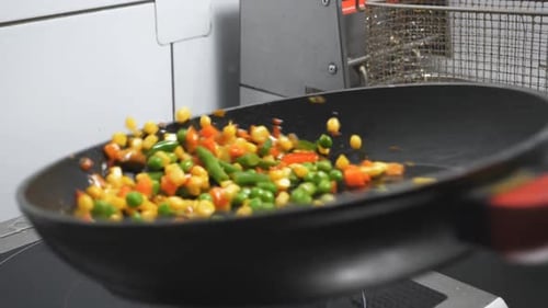 Male Arm of Cook Holding Skillet and Tossing Up Mixed Vegetables at Kitchen Restaurant
