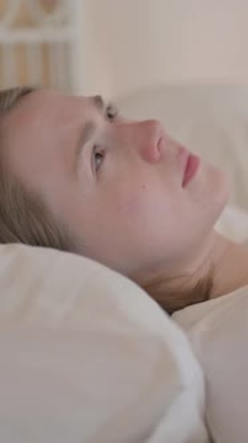 Side View of Brainstorming Young Woman Lying in Bed, vertical video