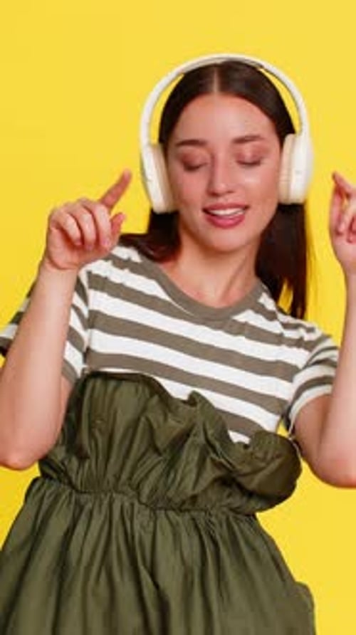 Woman with Headphones Dances with Dress on Yellow Background