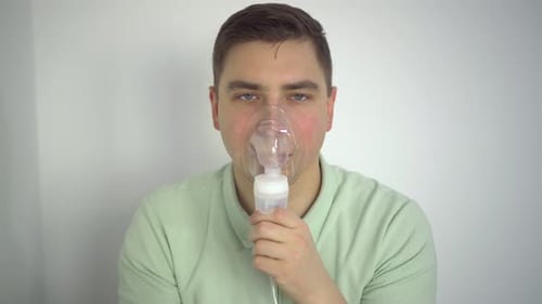 A Young Man Breathes Through an Inhaler Closeup A Man with an Oxygen Mask is Being Treated for a