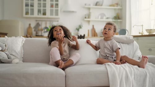 Children Play with Balloon on Sofa at Home