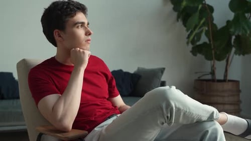 Young Man In Casual Attire Deep In Thought At Home During Daytime