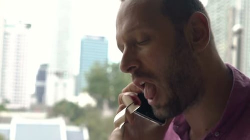 Young Man Talking on Phone at Cafe