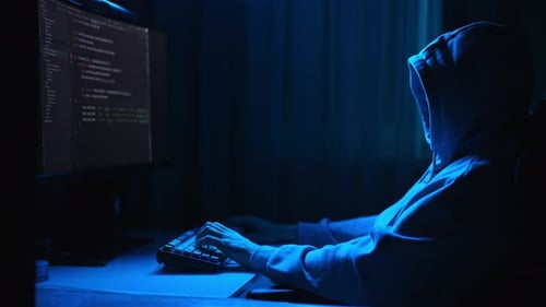 Side View of Hooded Hacker Male Getting Access to Computer System Hacking Into Database Cybercrime