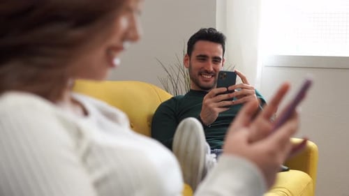 Couple Relaxing on Couch Using Mobile Phones