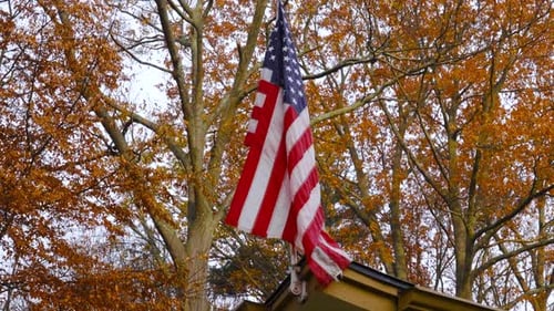 Tattered American Flag Flies Over Suburban Home in Autumn