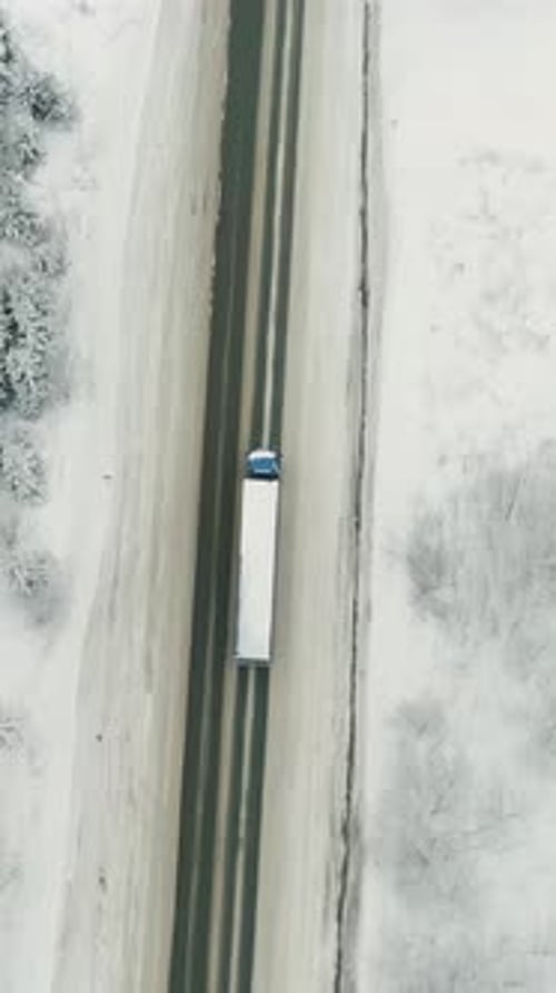 Conducción de camión a lo largo de la carretera a través del bosque de invierno: vista aérea de la conducción de un automóvil en la carretera de invierno