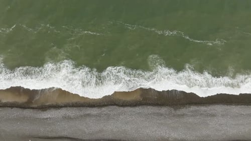 Aerial view The green sea water washes the shore of the beach with many small pebbles.