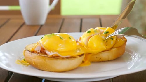 Knife Cuts into Delicious Eggs Benedict Breakfast