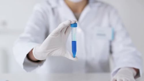 Lab Worker Holds Vial of Blue Liquid