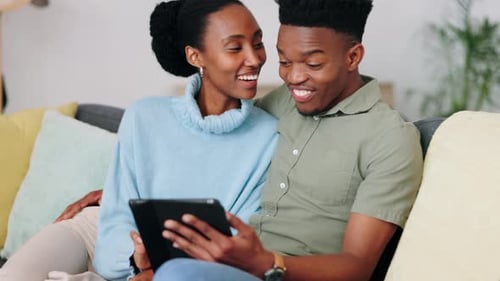 Laughing Couple Enjoying Tablet at Home on Sofa