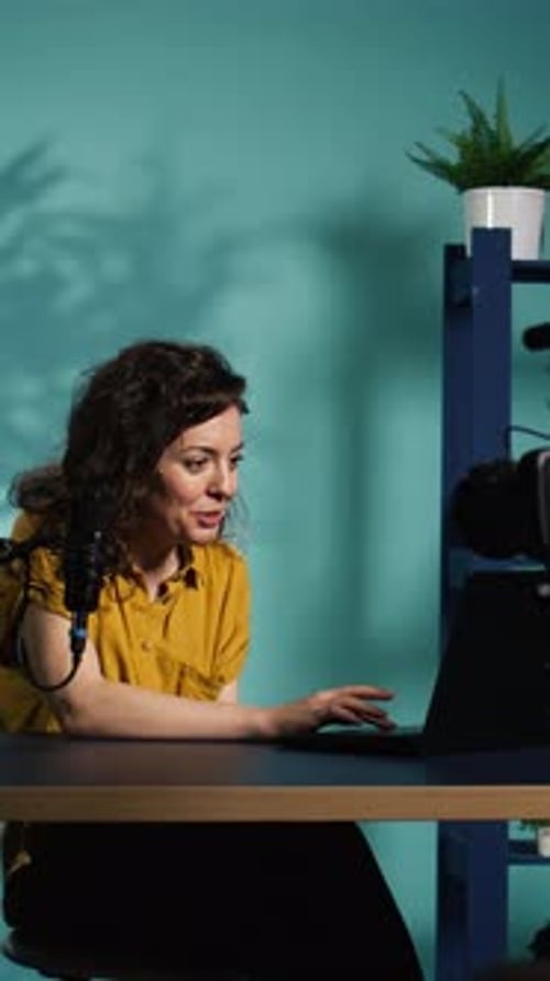 Woman Talking at Computer in Office with Microphone