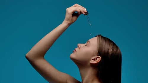 Woman Applies Serum to Face with Dropper
