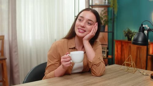 Dreamy Woman Enjoying Coffee at Desk Indoors