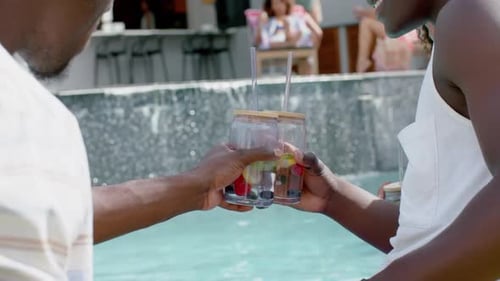 Friends Toasting with Drinks by Luxury Swimming Pool