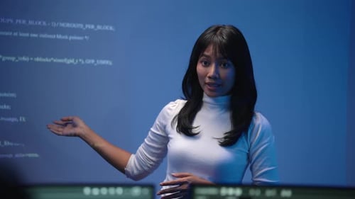 Asiatische Technikerin, die auf einem großen Bildschirm auf den Code zeigt