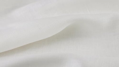 Soft folds of the white linen fabric rotates on the showcase. Top view of textile background.