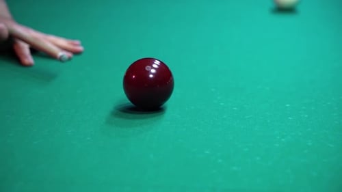Close-up man hits the red billiard ball