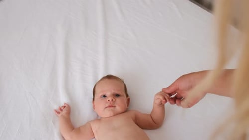 Baby Holding Mother's Hand on White Sheet