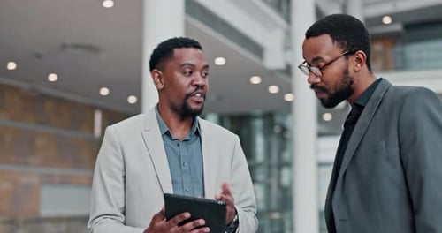Businessmen Discussing Data on Tablet in Modern Lobby