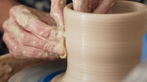 Une potière travaille sur un tour de potier et fabrique un pot en céramique en argile dans un atelier de poterie.