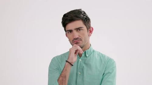 Portrait, thinking and a confused man in studio, standing hand on chin against a gray background