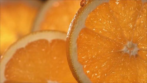 Drop of Orange Water Flows Down the Surface of a Ripe Juicy Orange Slice
