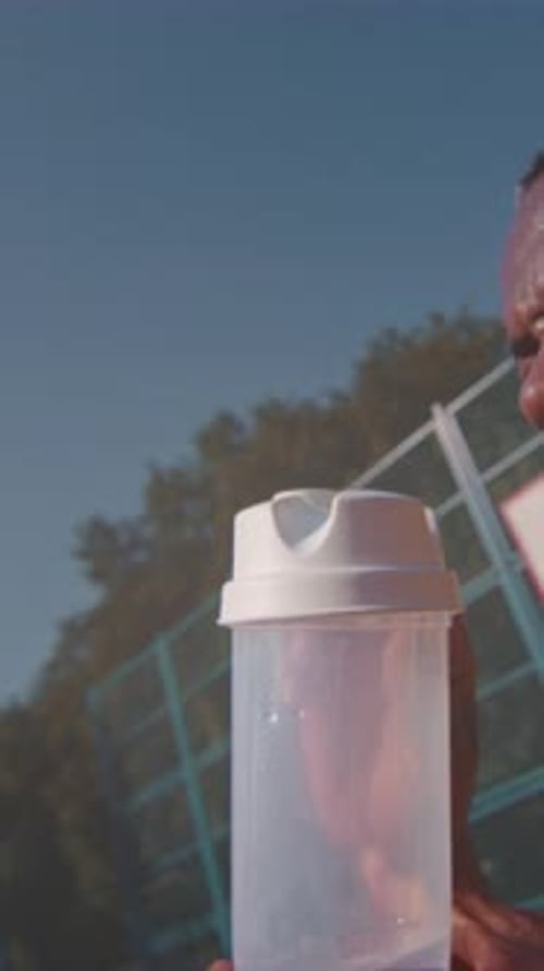 Man Drinks from Shaker on Sports Field