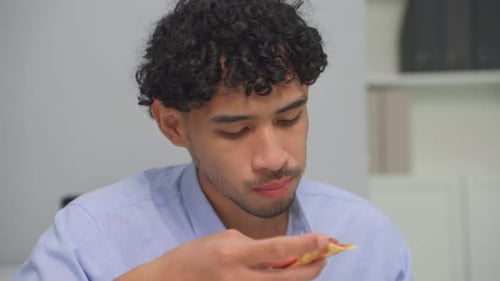 Asian young businessman eating homemade pizza while working in office.