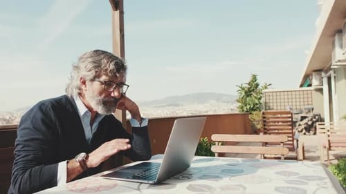 Man Works on Laptop on Urban Rooftop