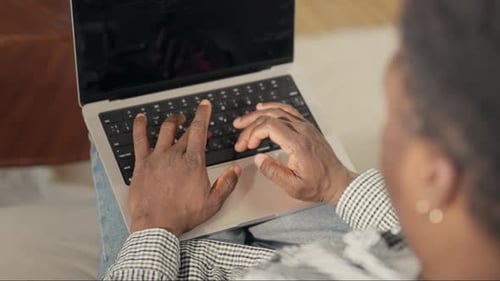 Adult Black Man Typing Text on Keyboard of Modern Laptop Working Remotely Closeup View of Computer