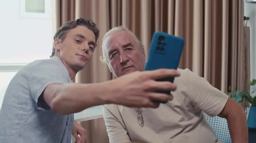 Young Man and Senior Man Taking Selfie Together