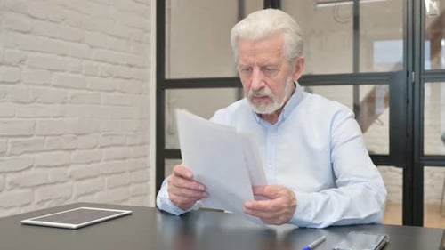 Senior Man Reviewing Documents at Desk