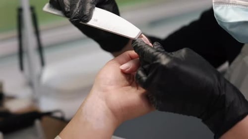 Manicurist Filing Client Nails in a Bright Salon