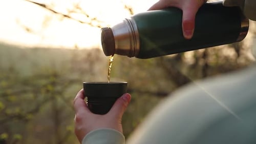 Woman Pouring Tea From Thermos