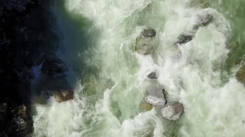 An einem strahlend sonnigen Frühlingstag fließt eine Flussströmung durch das Tal rund um die glatten Felsen