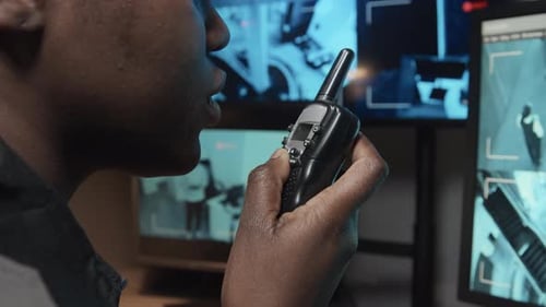 Man Communicates Over Walkie Talkie While Watching Security Footage