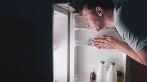 Man Searches Refrigerator for Late Night Snack