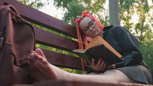 Young Woman Relaxing and Reading on Park Bench