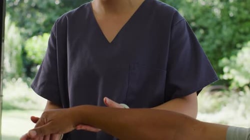 Mulher asiática esfoliando o antebraço do paciente enquanto homem estendendo o braço na janela, verificando o alinhamento
