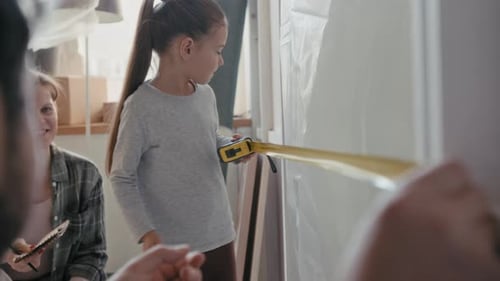 Girl Measuring Doorway Width and Saying Result to Her Mother