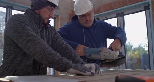 Construction Workers Cutting Metal with Angle Grinder Indoors