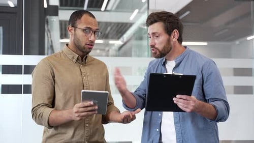 Two angry businessmen arguing intensely standing in modern office, showcasing conflict and emotion
