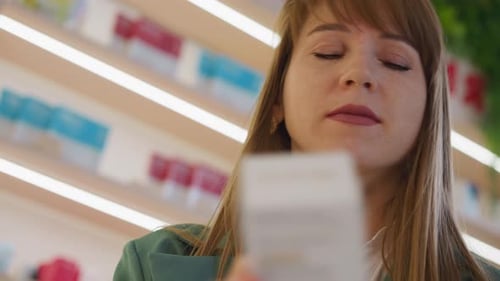 Focused Woman Reads Instructions to Dietary Supplement Pills